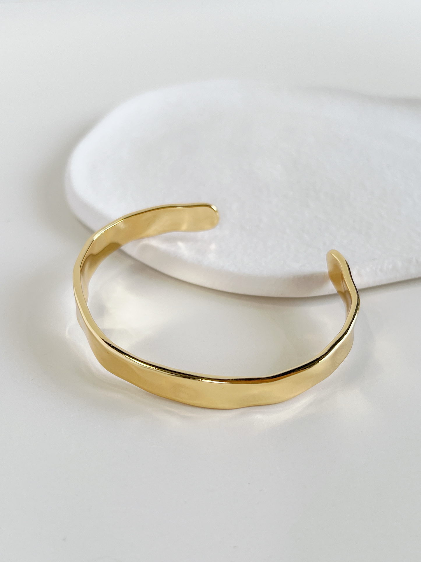 Close-up of the smooth interior finish and semi-malleable architecture of a premium gold hammered cuff bracelet.