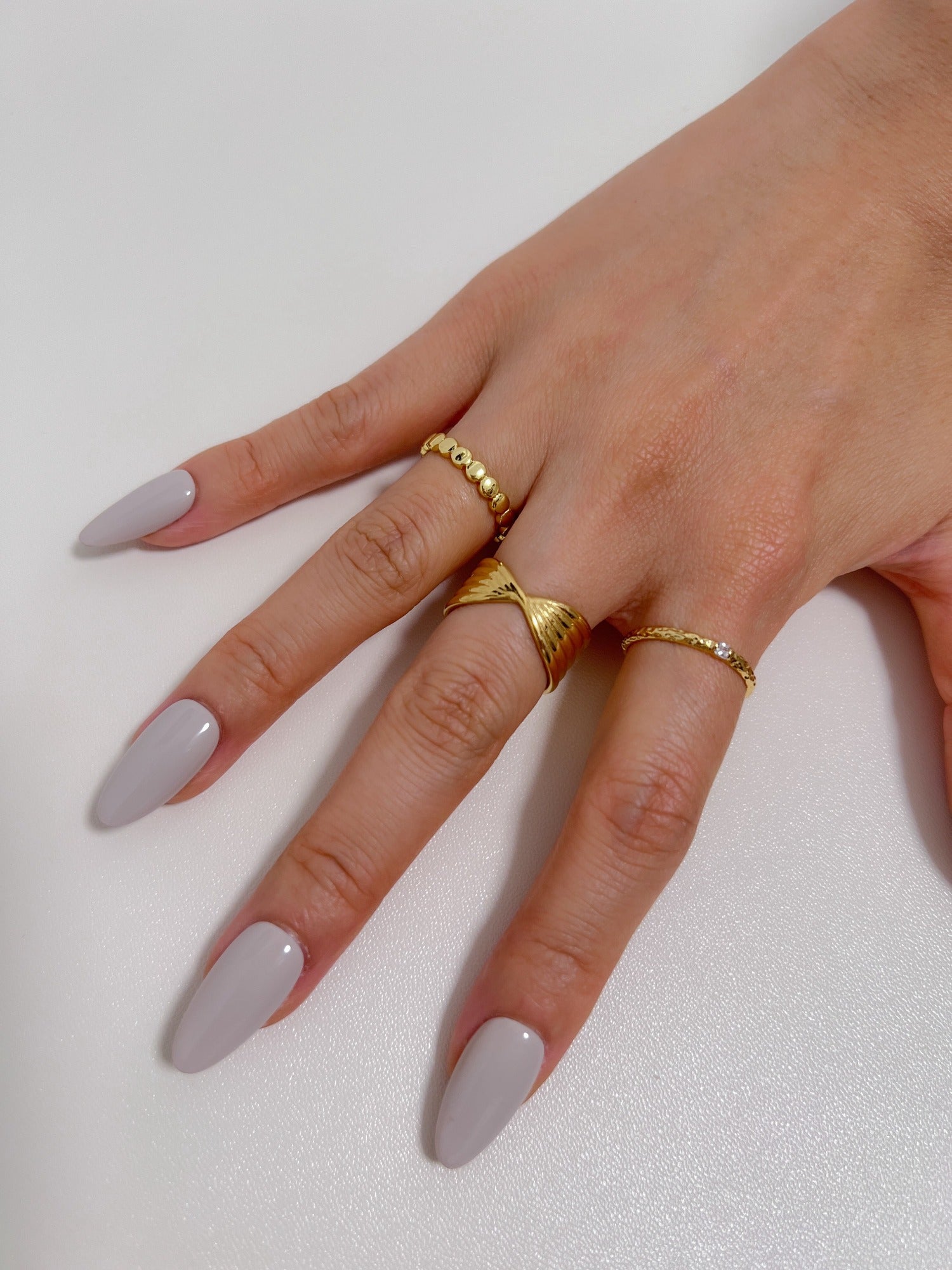 Lifestyle hand styling showing the June gold crossover ring and stacking gold band on a model's finger