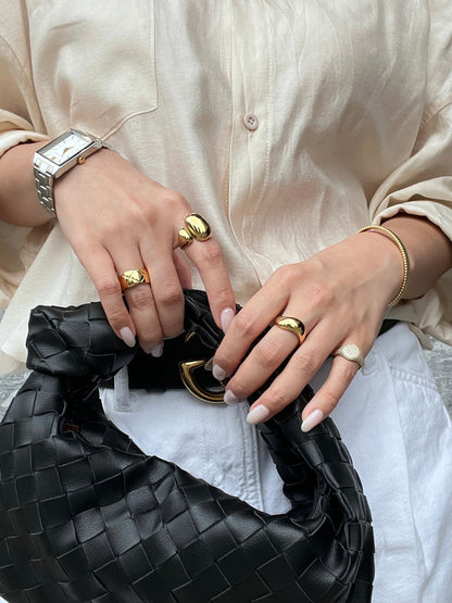 High-mirror gold sculptural ring catching light on model's finger