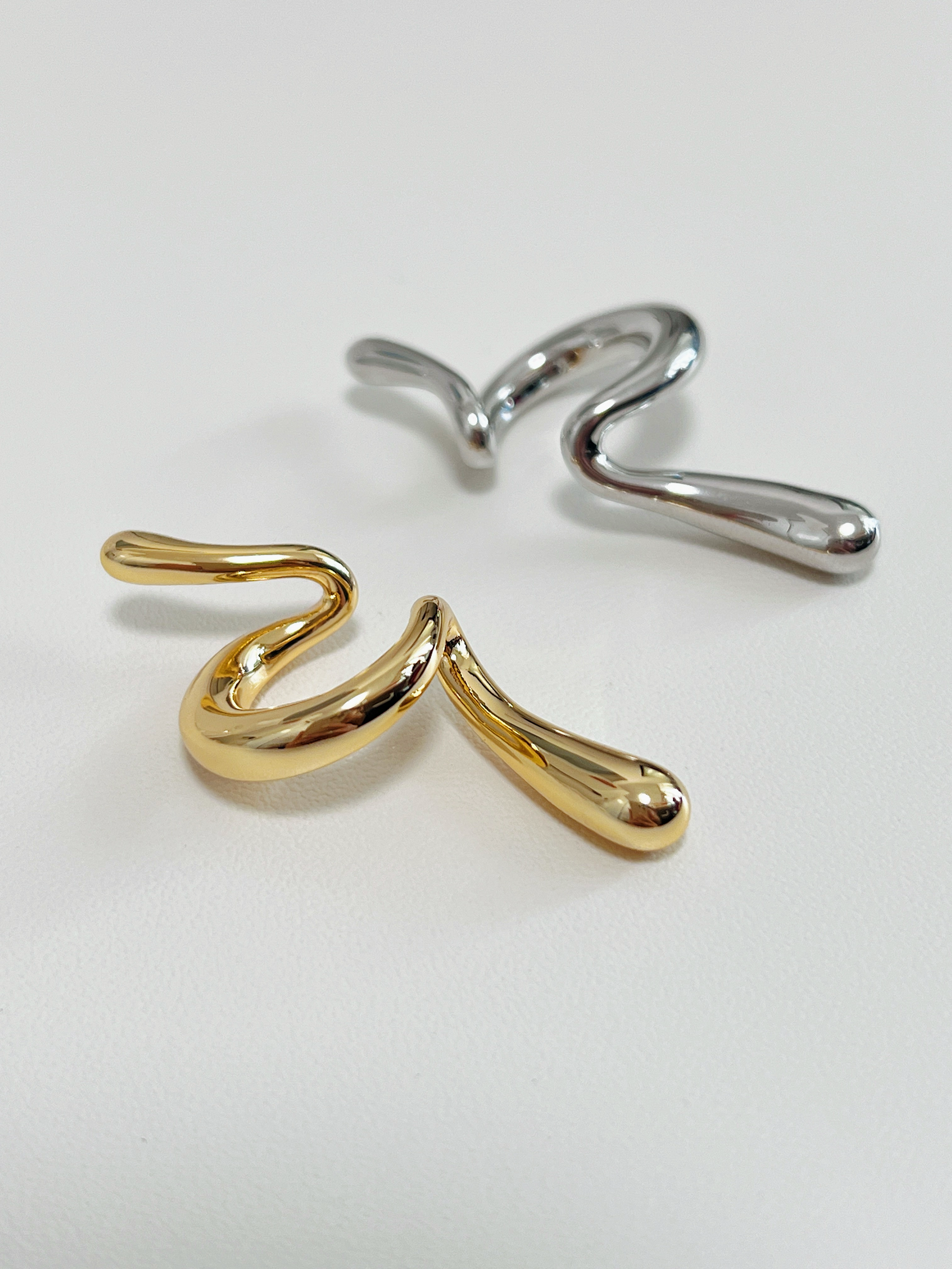 Close-up of gold Parker Curve Abstract Ear Cuff showing the fluid, melted metal design.