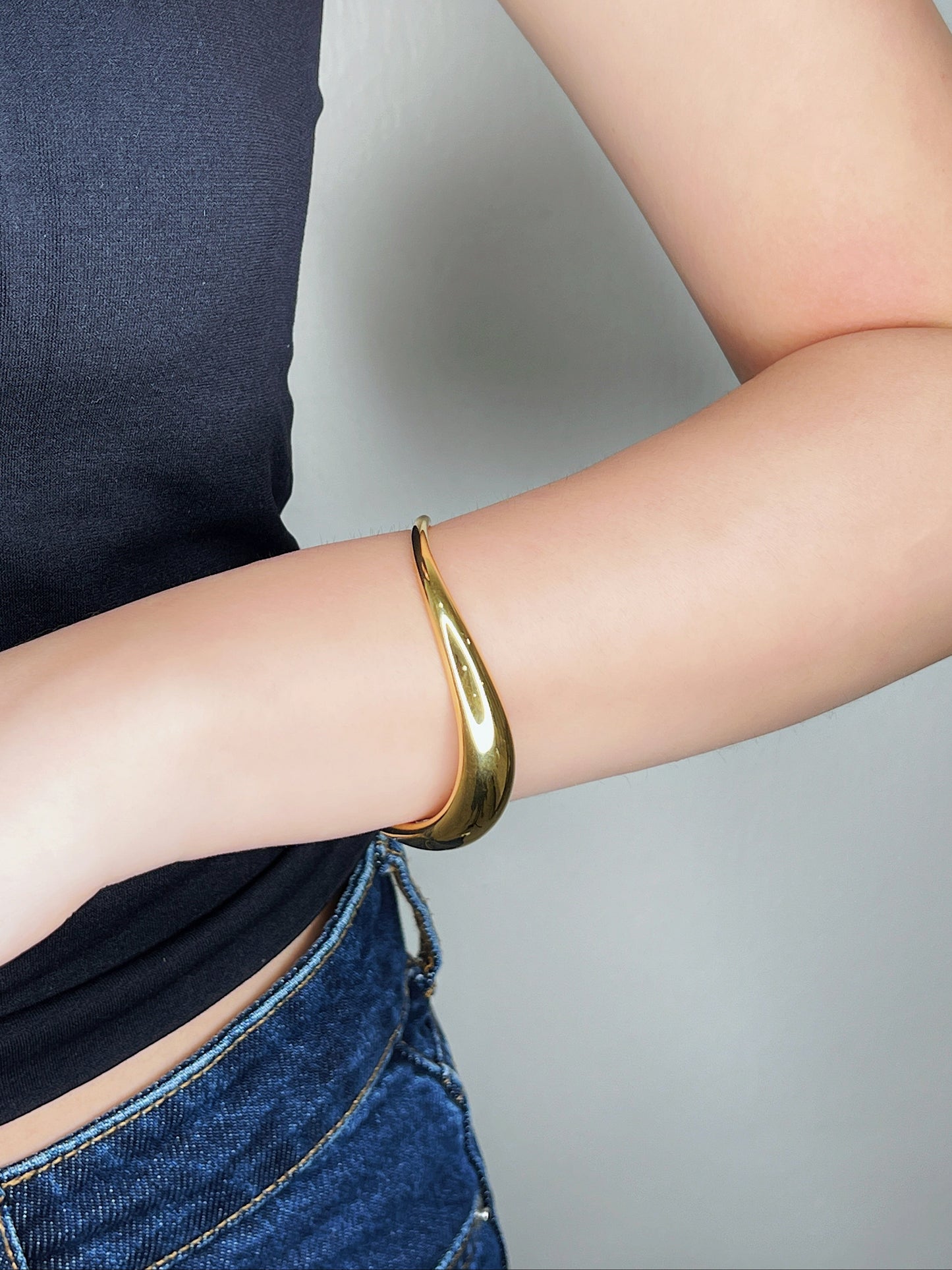 Mid-shot of a model's arm, framing the Vicky sculpted gold cuff as the singular statement piece against black apparel.