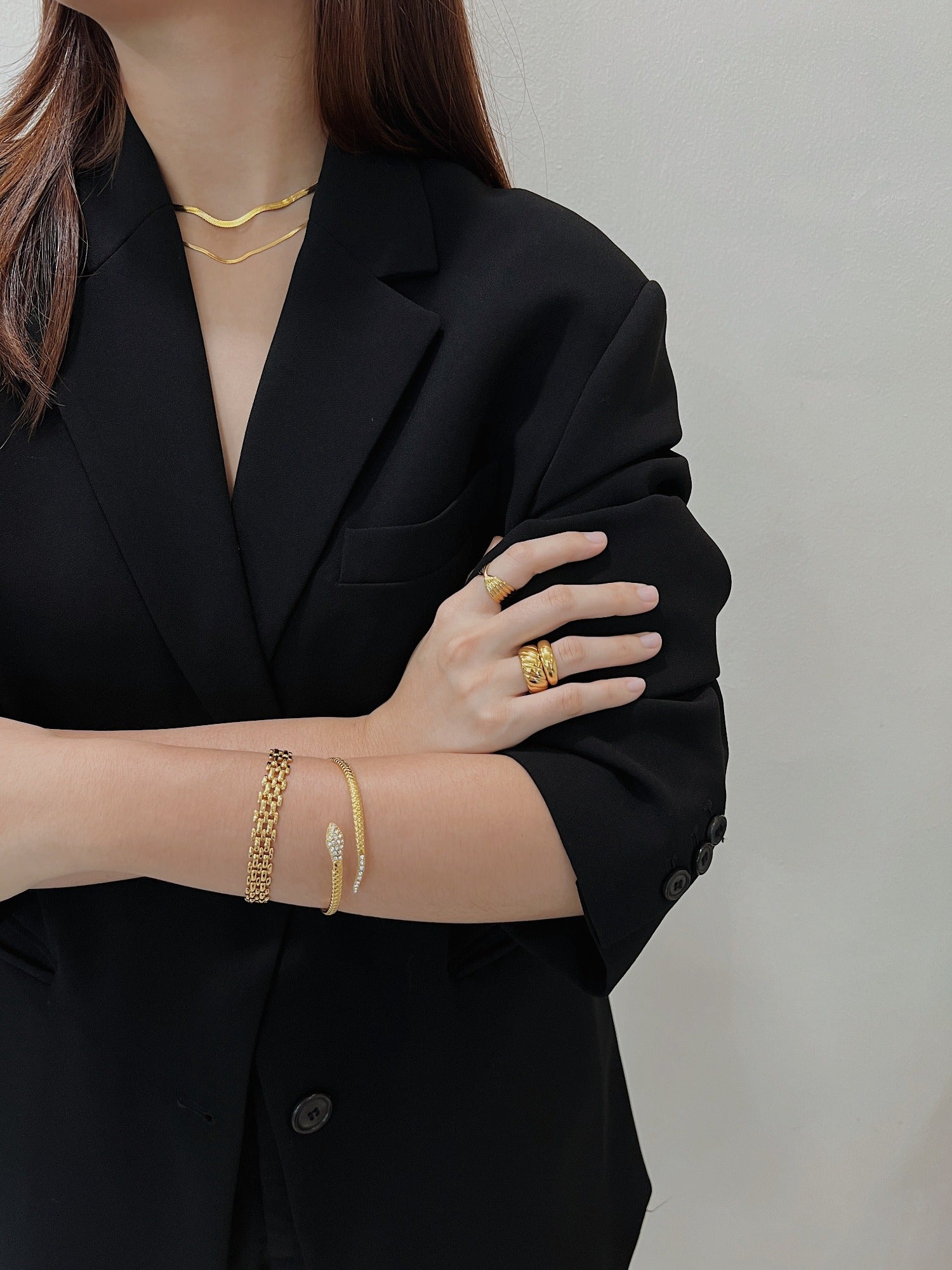 Model arms crossed wearing the 18K gold Isa Serpent Bangle, highlighting CZ sparkle against black fabric.