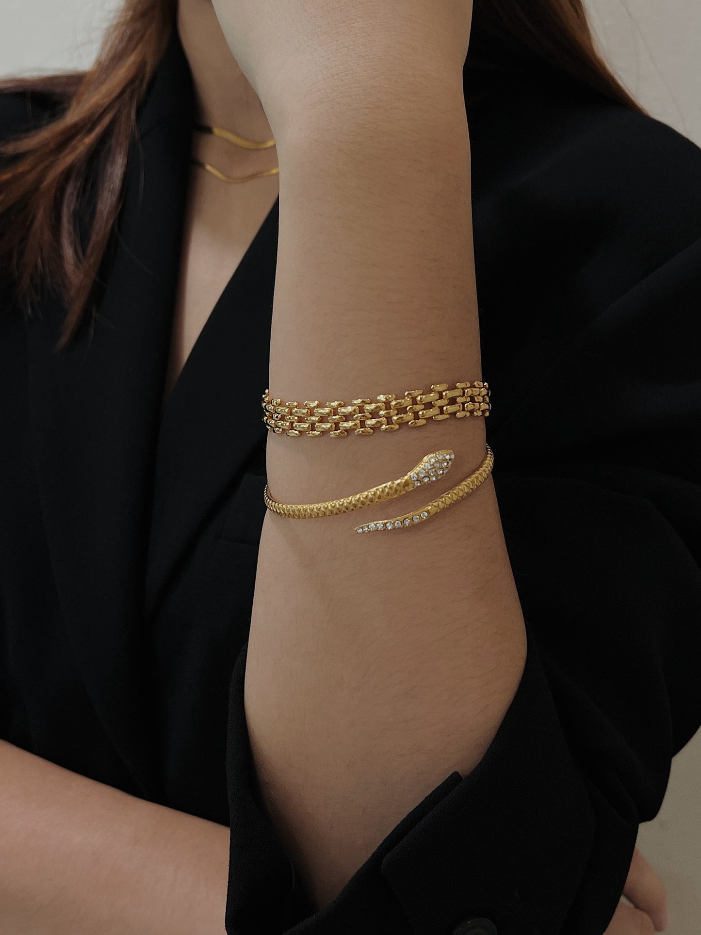 Model arm angled to demonstrate the effortless stacking versatility of the gold Isa Serpent Bangle.