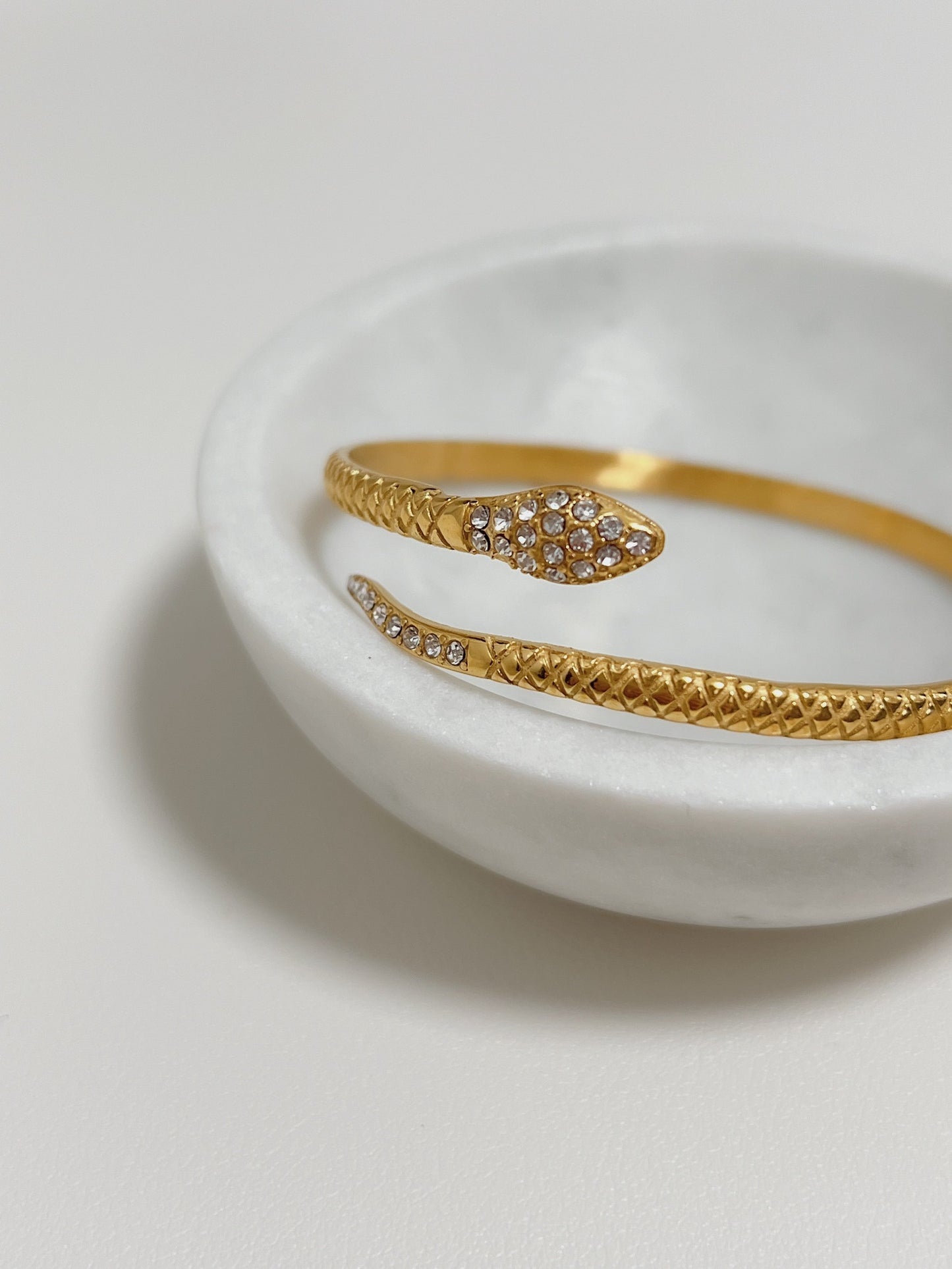 Macro view showing the intricate carved scale texture along the band of the Isa gold snake cuff.