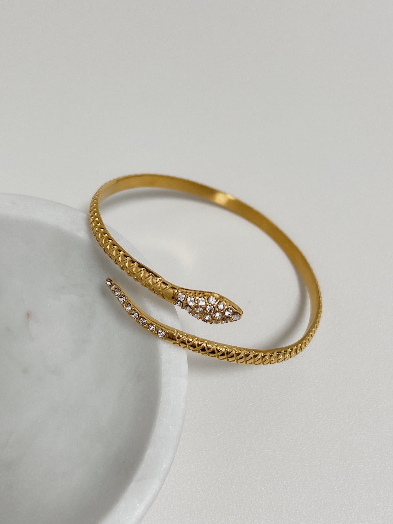 Top-down angle displaying the ergonomic open bypass silhouette of the Isa gold snake bracelet.
