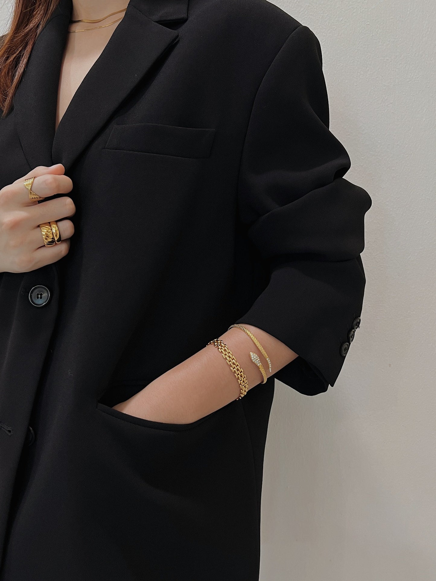 Hand in blazer pocket demonstrating how the Isa Serpent Bangle sits comfortably without slipping.