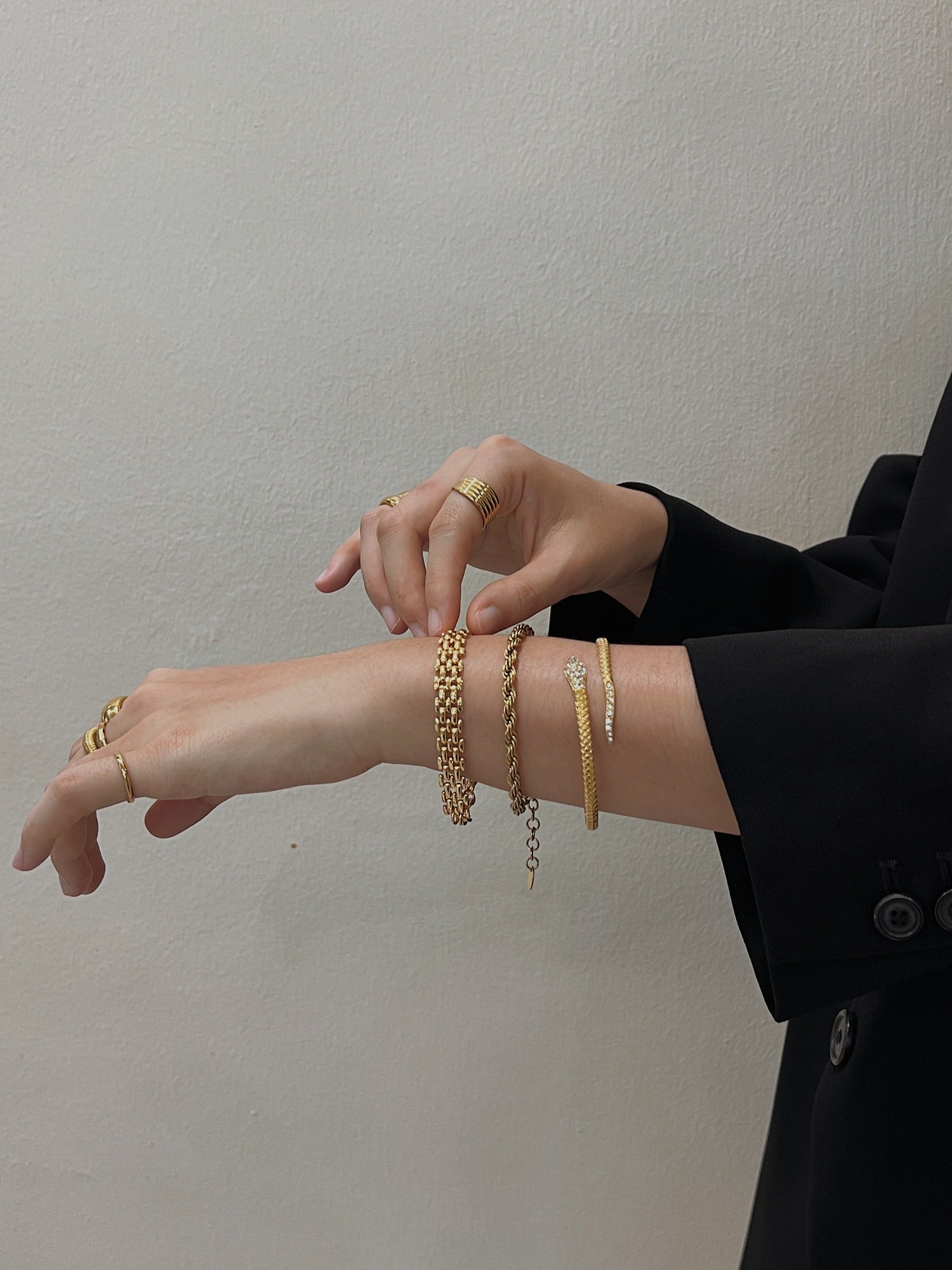 Close-up model shot of the Isa Serpent Bangle resting on wrist alongside gold rope and link bracelets.