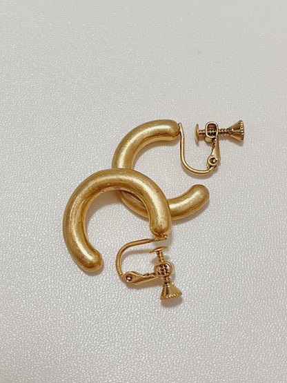 Macro detail shot of the hand-brushed satin surface texture on the Zora gold clip-on demi-hoop earrings.