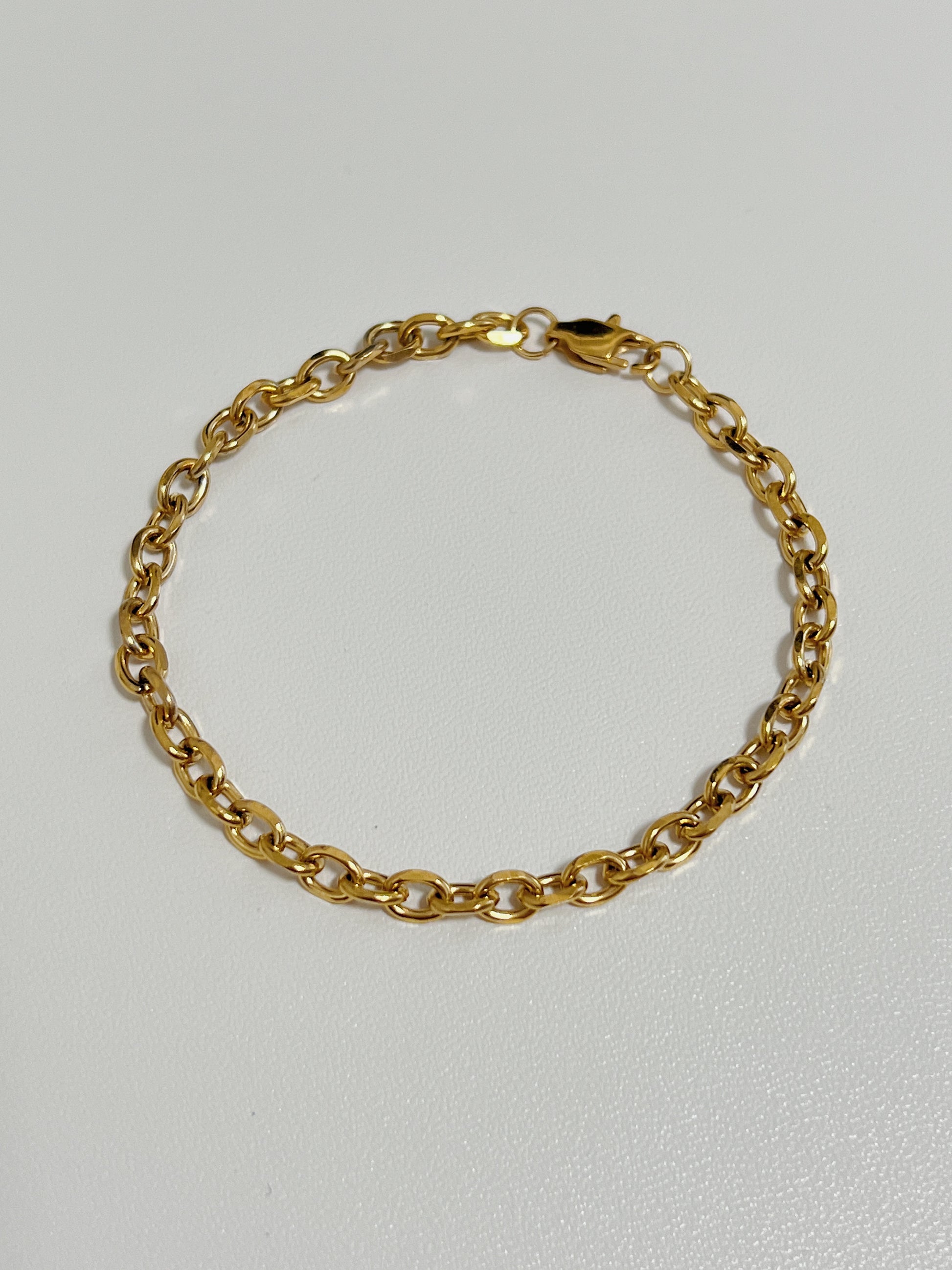 A gold trixie cable chain bracelet on a white background.