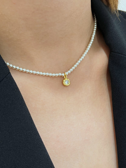 Side lookbook perspective of a model modeling a 4mm micro pearl strand with an organic crystal charm on a bare collarbone