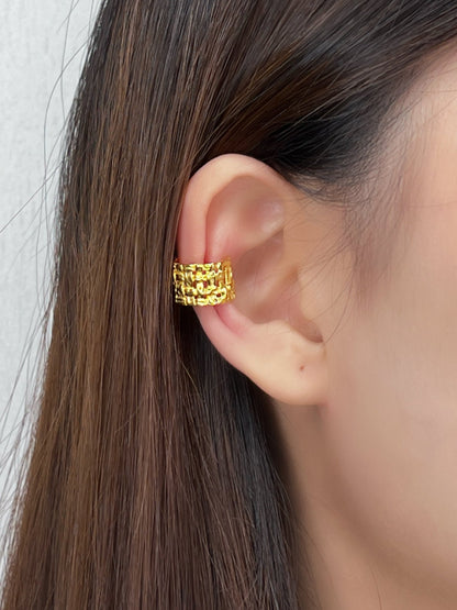 Model wearing the gold Carmela Woven Cuff on the mid-conch for a textural luxury statement.