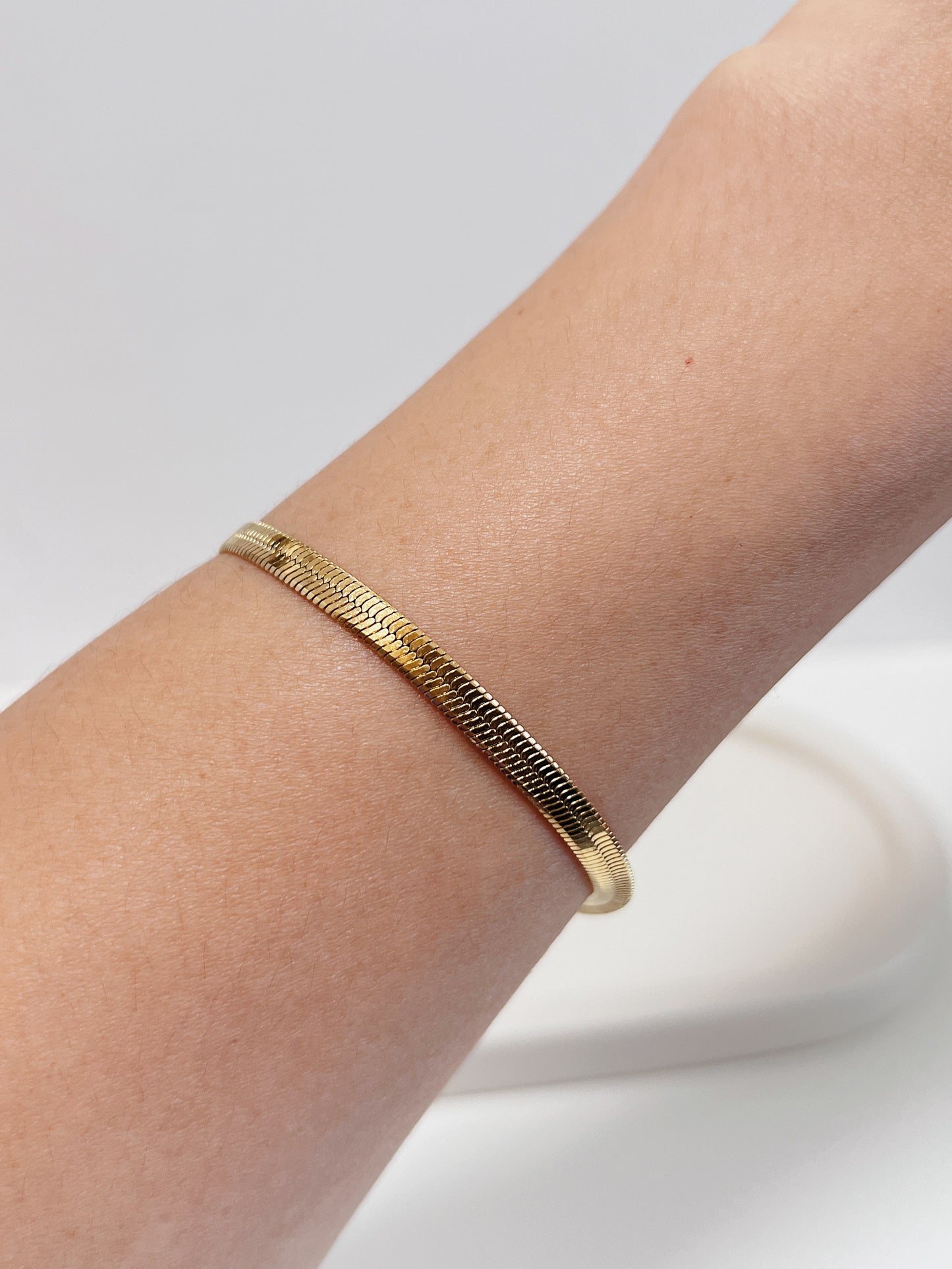 Close-up on-model perspective of the Bec 18K gold PVD serpentine chain bracelet lying perfectly flat on a bare arm, showing its seamless fit