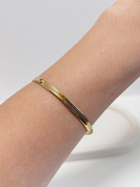 Close-up on-model perspective of the Bec 18K gold PVD serpentine chain bracelet lying perfectly flat on a bare arm, showing its seamless fit