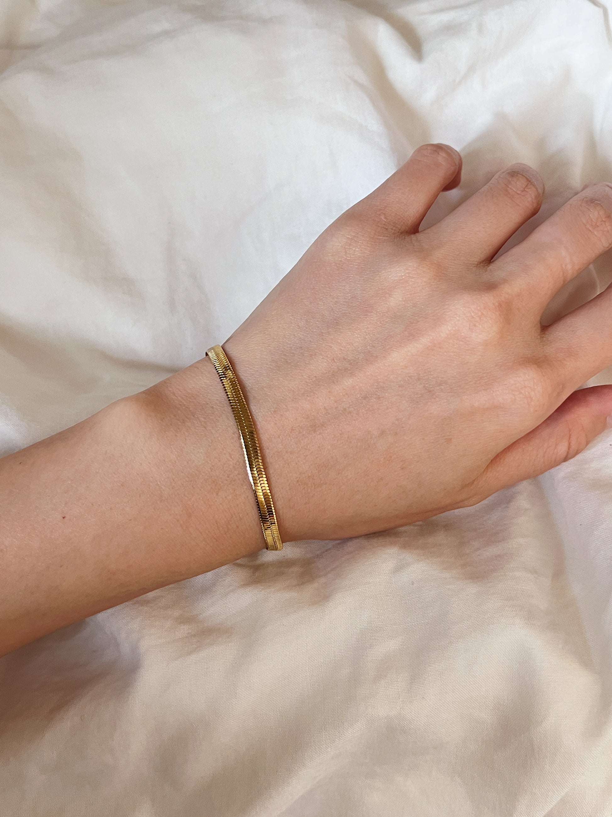 On-model layout showcasing the slim Bec herringbone bracelet styled flat on a bare arm.