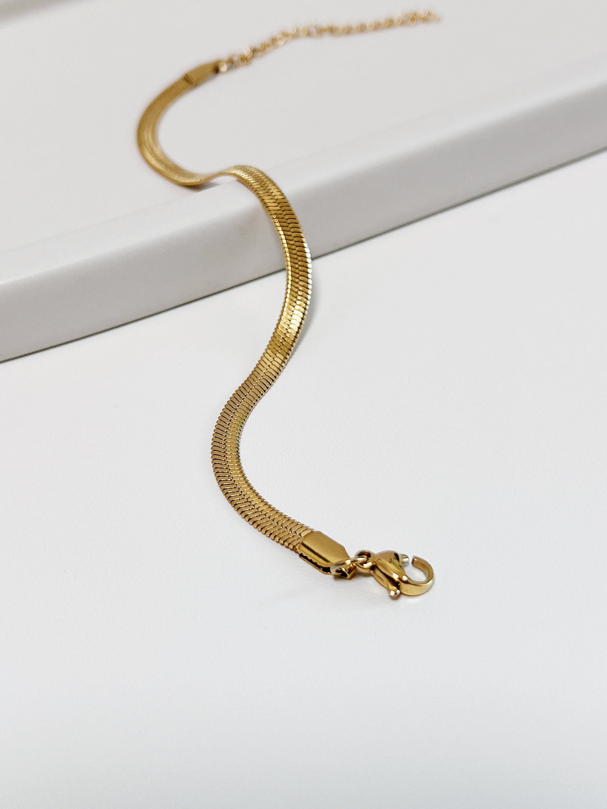Still life capture capturing natural light reflecting off the highly polished golden surface of the Bec serpentine chain.