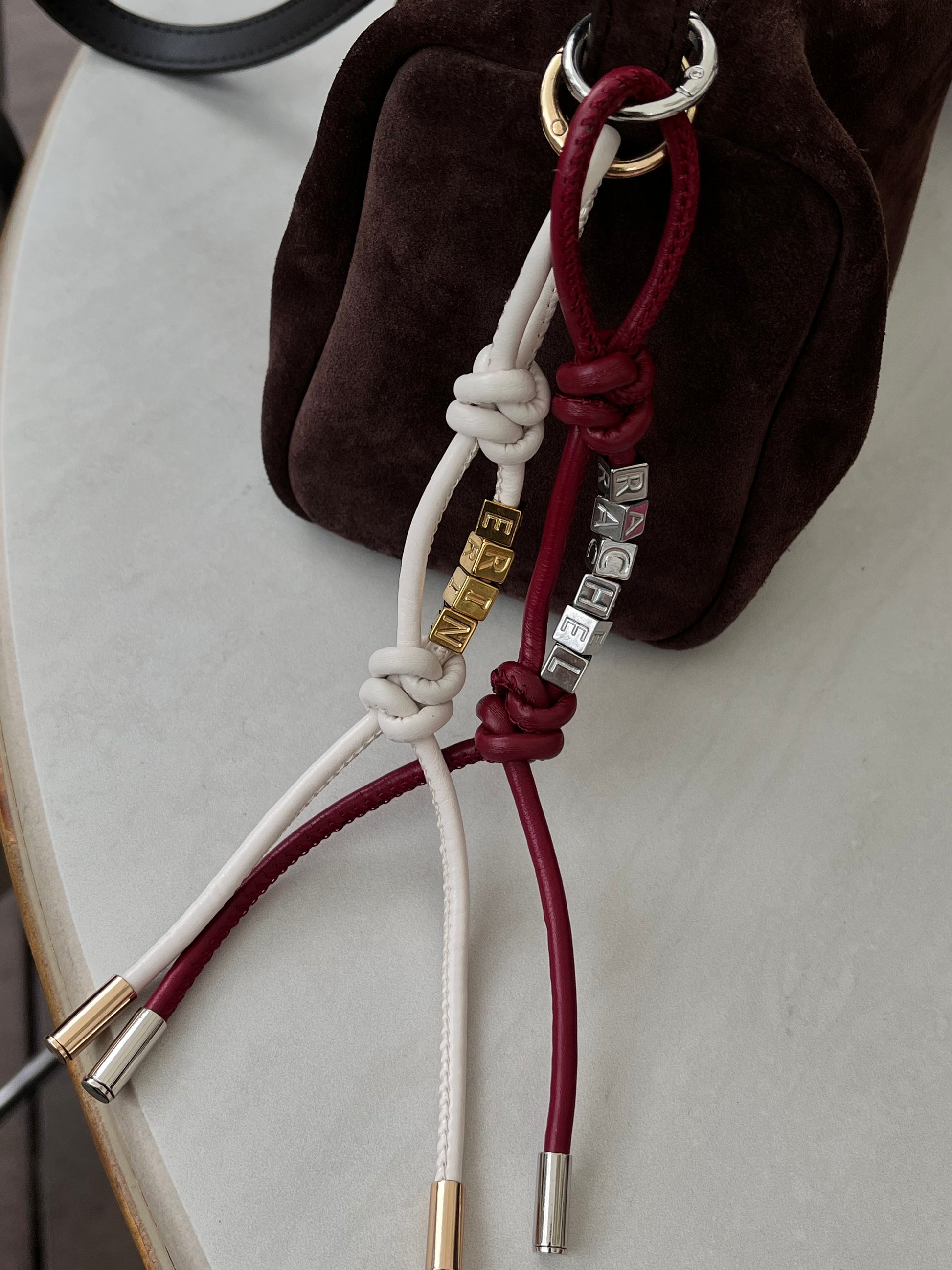 Close-up of gold initial beads and silver initial beads on leather charm.