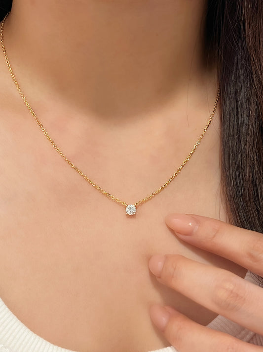Model with hand resting on chest wearing Cala 14k gold plated moissanite solitaire pendant necklace