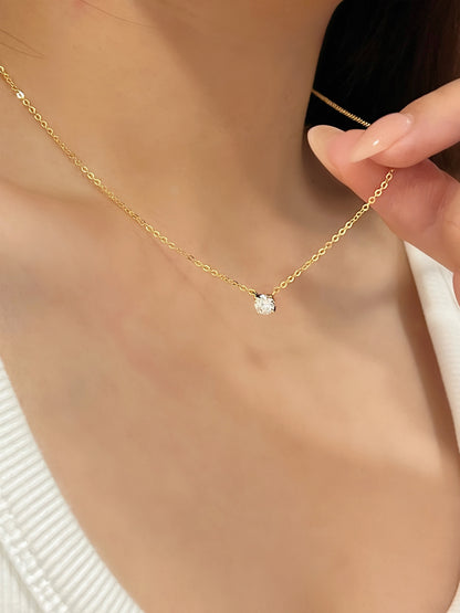 Model fingers holding fine trace chain of Cala 14k gold plated moissanite solitaire pendant necklace on collarbone