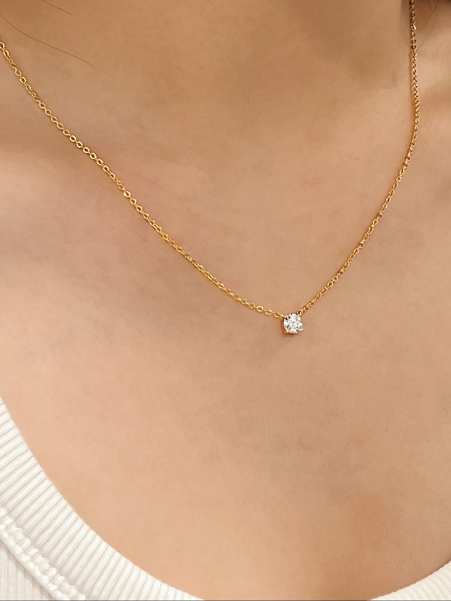 Model highlighting brilliant round VVS1 moissanite stone on Cala 14k gold finish solitaire pendant necklace