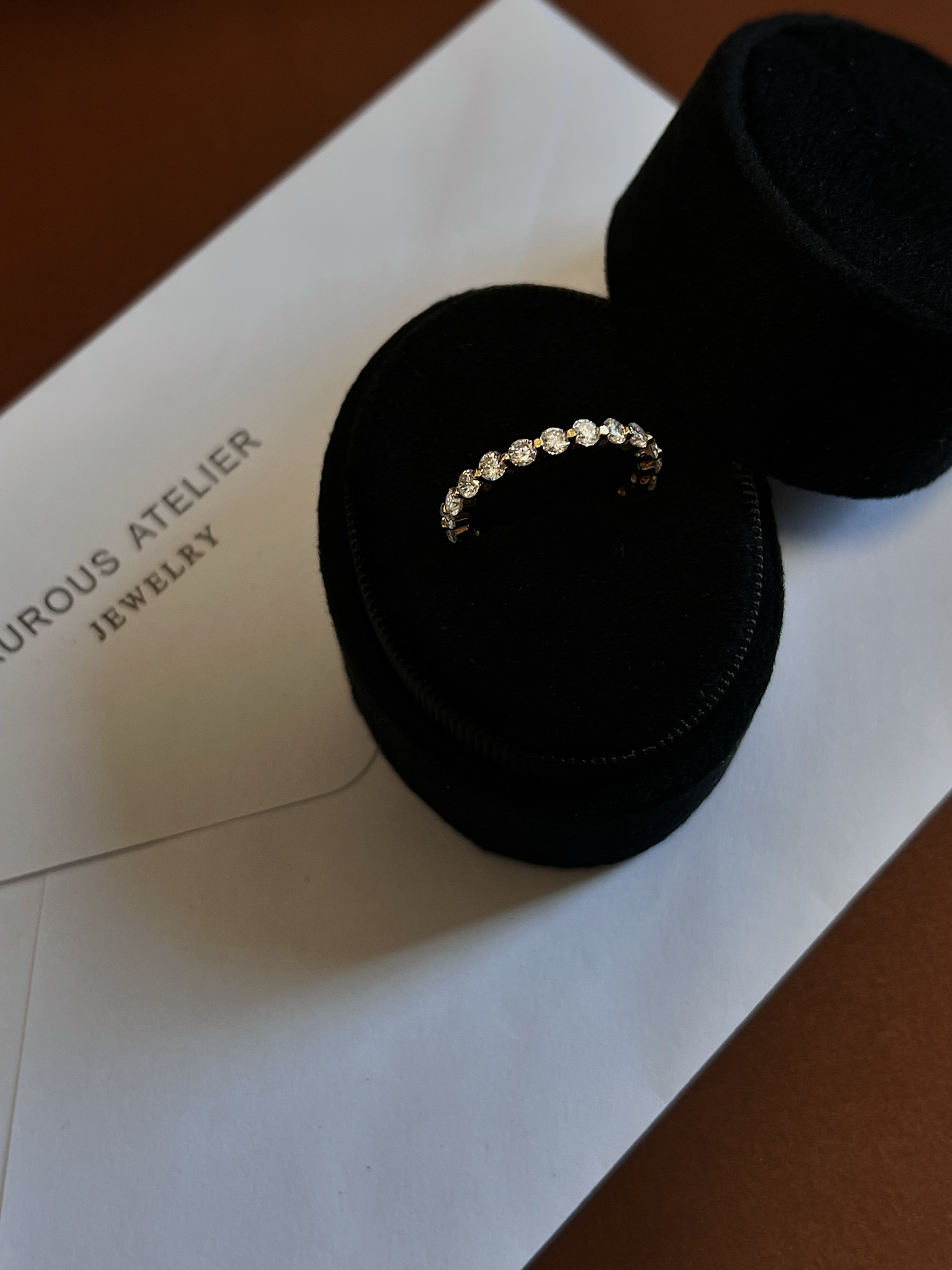 Low profile open gallery design of an 18k gold vermeil full eternity ring catching ambient studio lighting