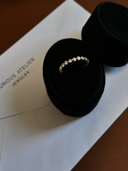 Low profile open gallery design of an 18k gold vermeil full eternity ring catching ambient studio lighting