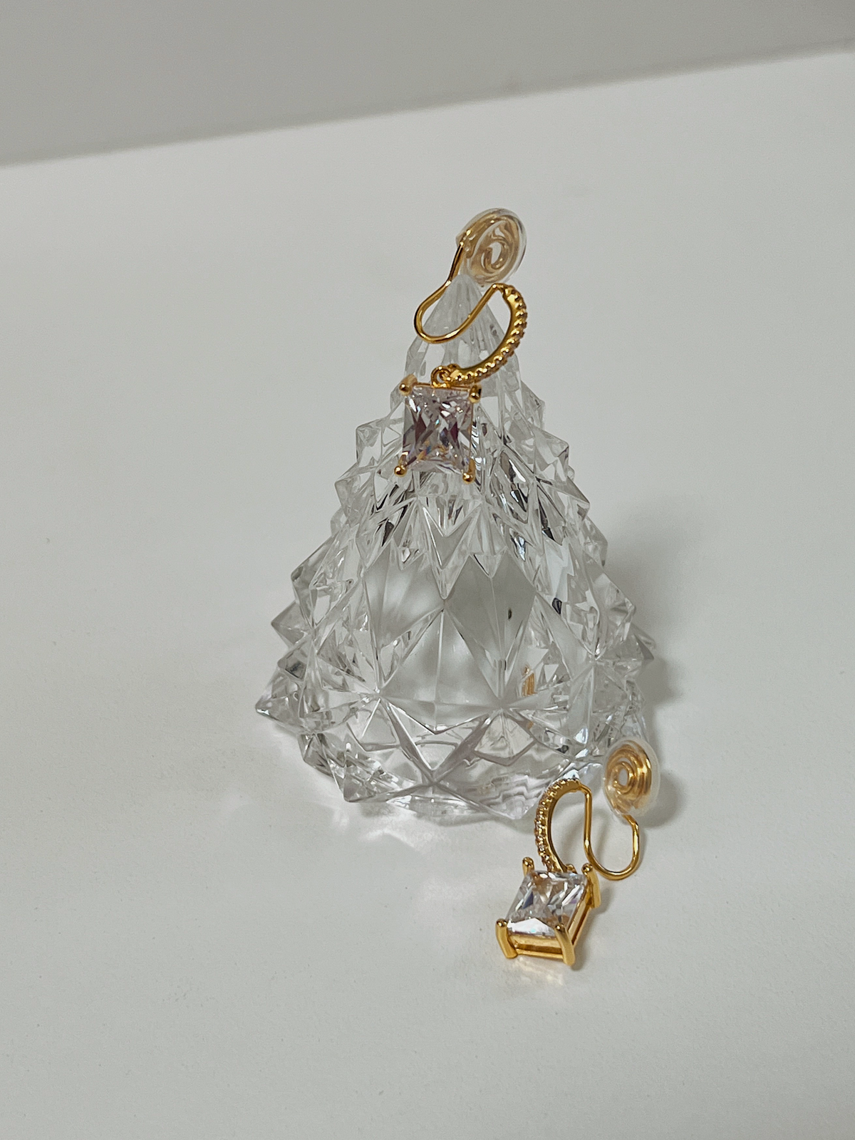 Studio lighting catching the brilliant facets of two gold emerald cut CZ clip-on earrings