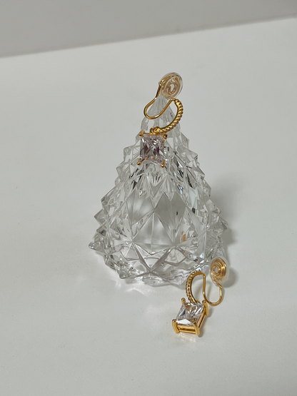 Studio lighting catching the brilliant facets of two gold emerald cut CZ clip-on earrings