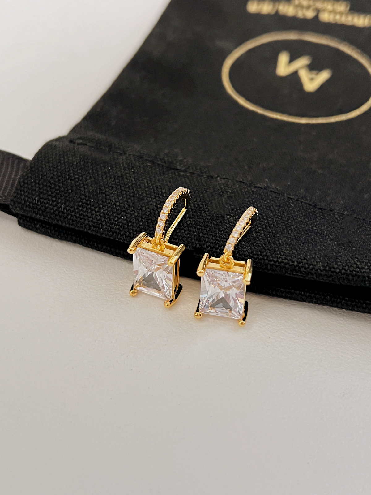 Front view showing micro-pavé CZ bar and dangling emerald cut crystal stone in 14K gold plating