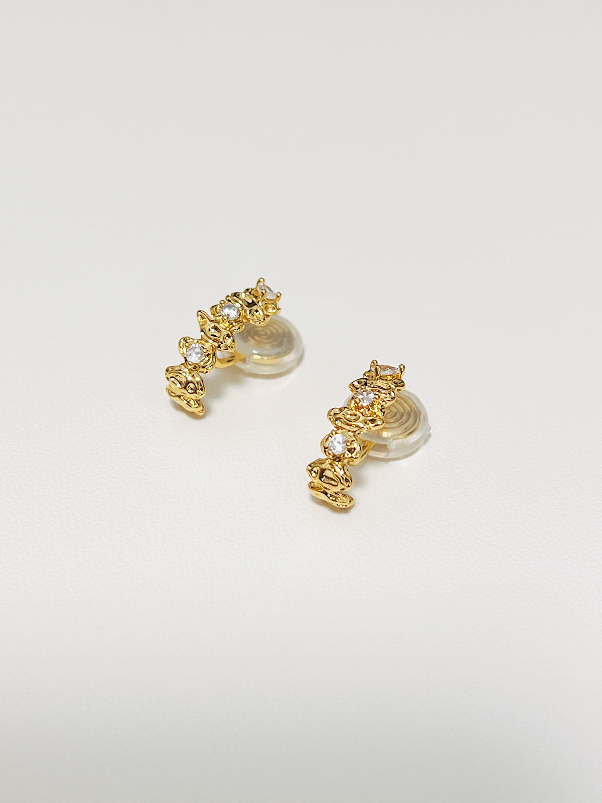 An overhead studio capture of the Celeste Astral climber clip-on earrings displayed flat on white surface