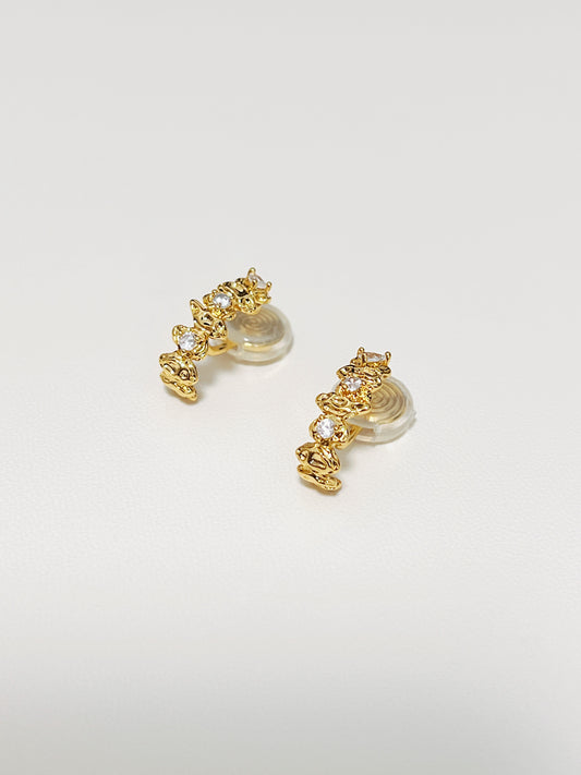 An overhead studio capture of the Celeste Astral climber clip-on earrings displayed flat on white surface