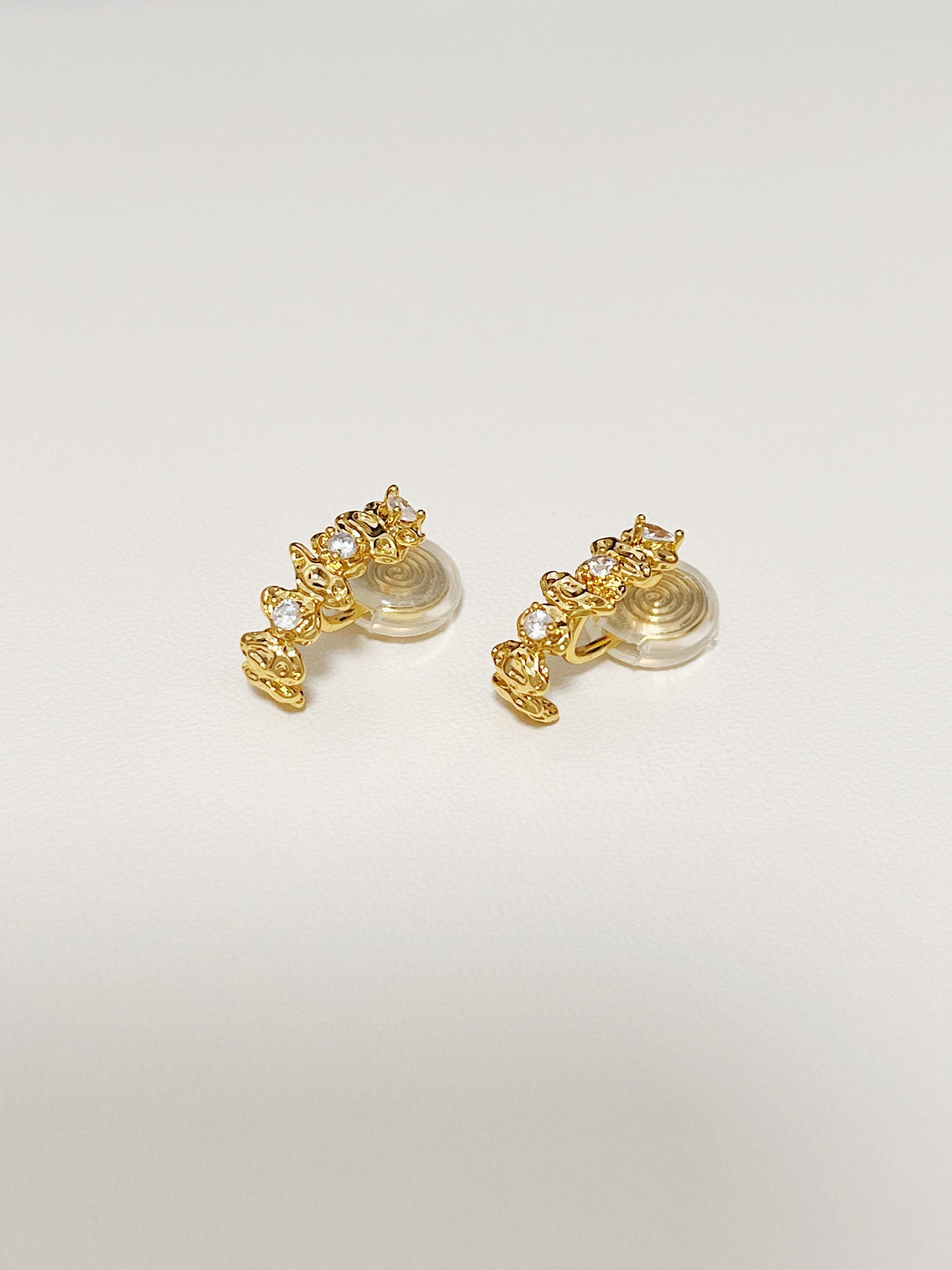 Aurous Atelier studio setting showcasing the Celeste astral climber clip-on earrings resting on a textured leather white background