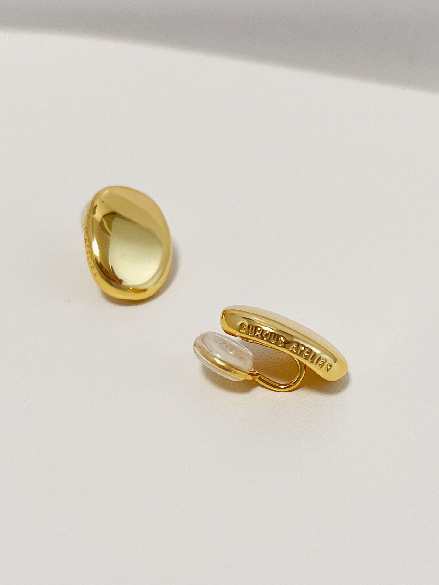 Close-up view of the smooth metallic curves of the Margaux chunky gold oval clip on earrings.