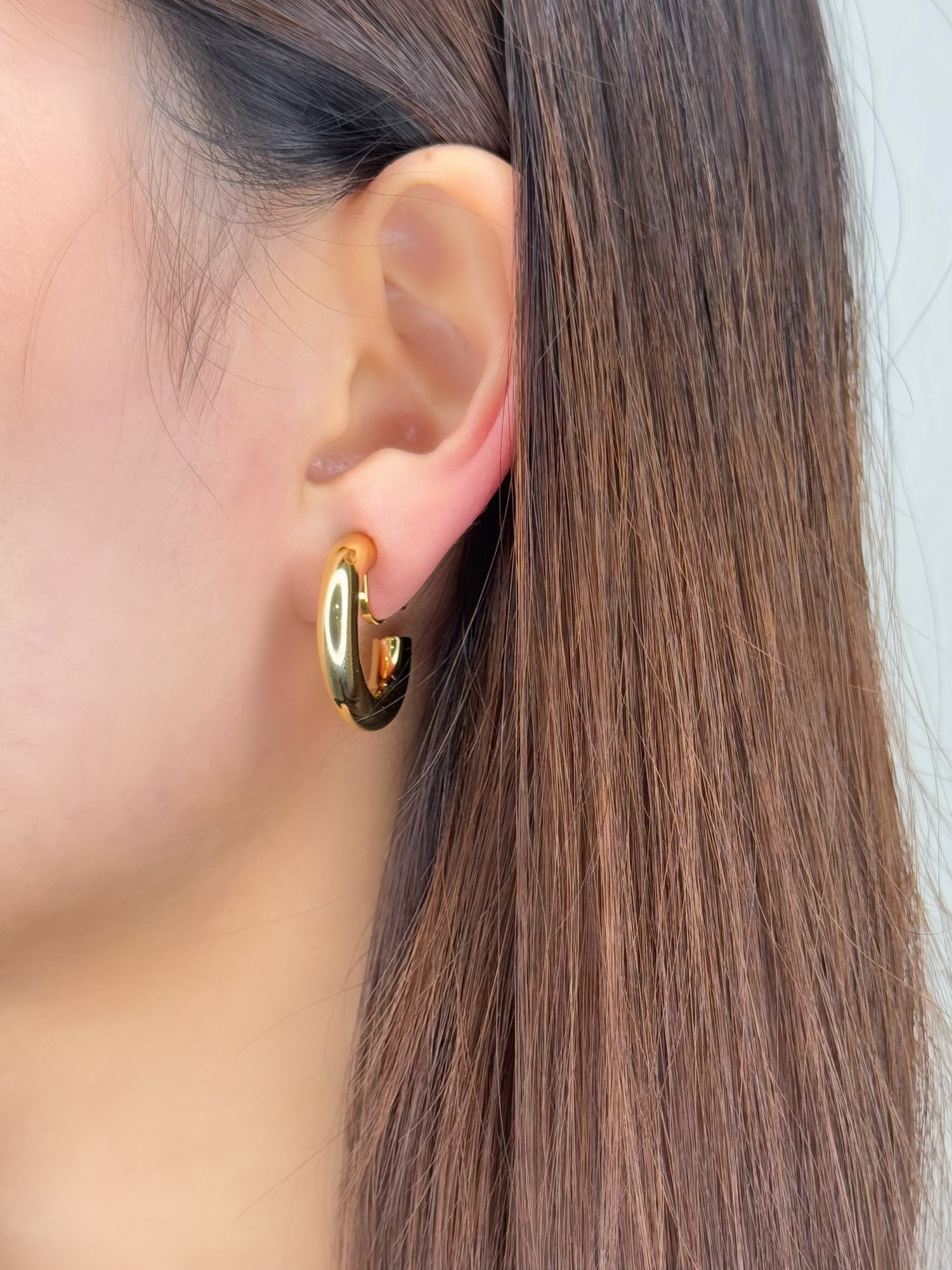 Corporate styling rotation featuring an unpierced collector wearing structural gold hoop jewelry accents