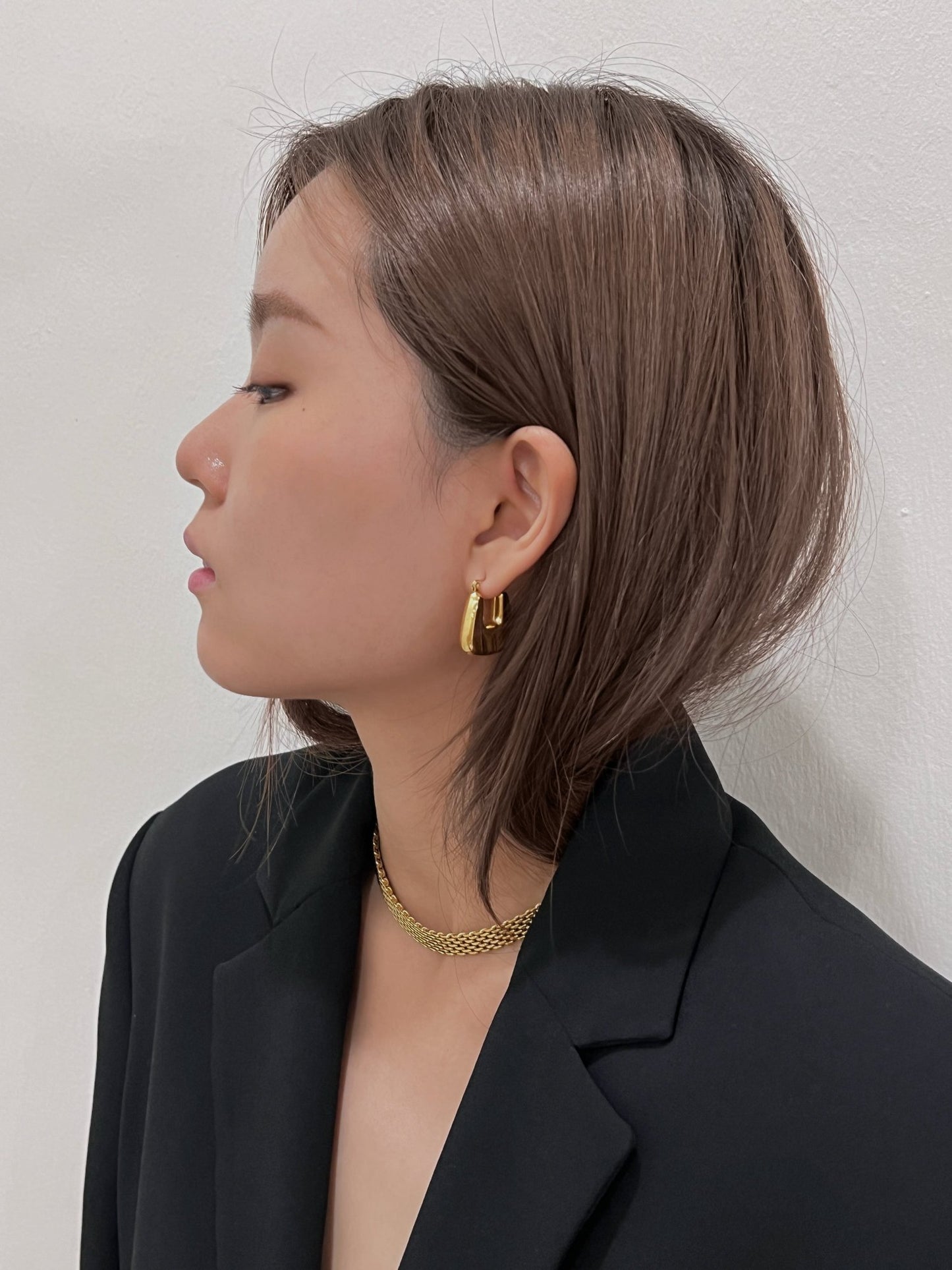 Creative director style snapshot pairing a heavy gold mesh necklace with an oversized sharp shoulder suit jacket