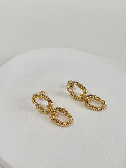 Independent atelier design showcasing organically distorted liquid metal textures on an elegant jewelry drop