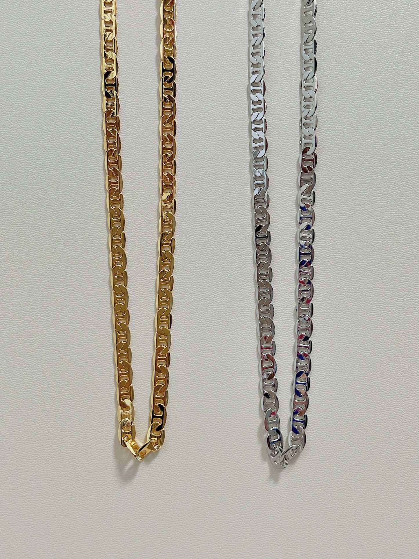 Close-up studio shot of a high-shine dual-tone precious metal selection featuring block-shaped nautical links