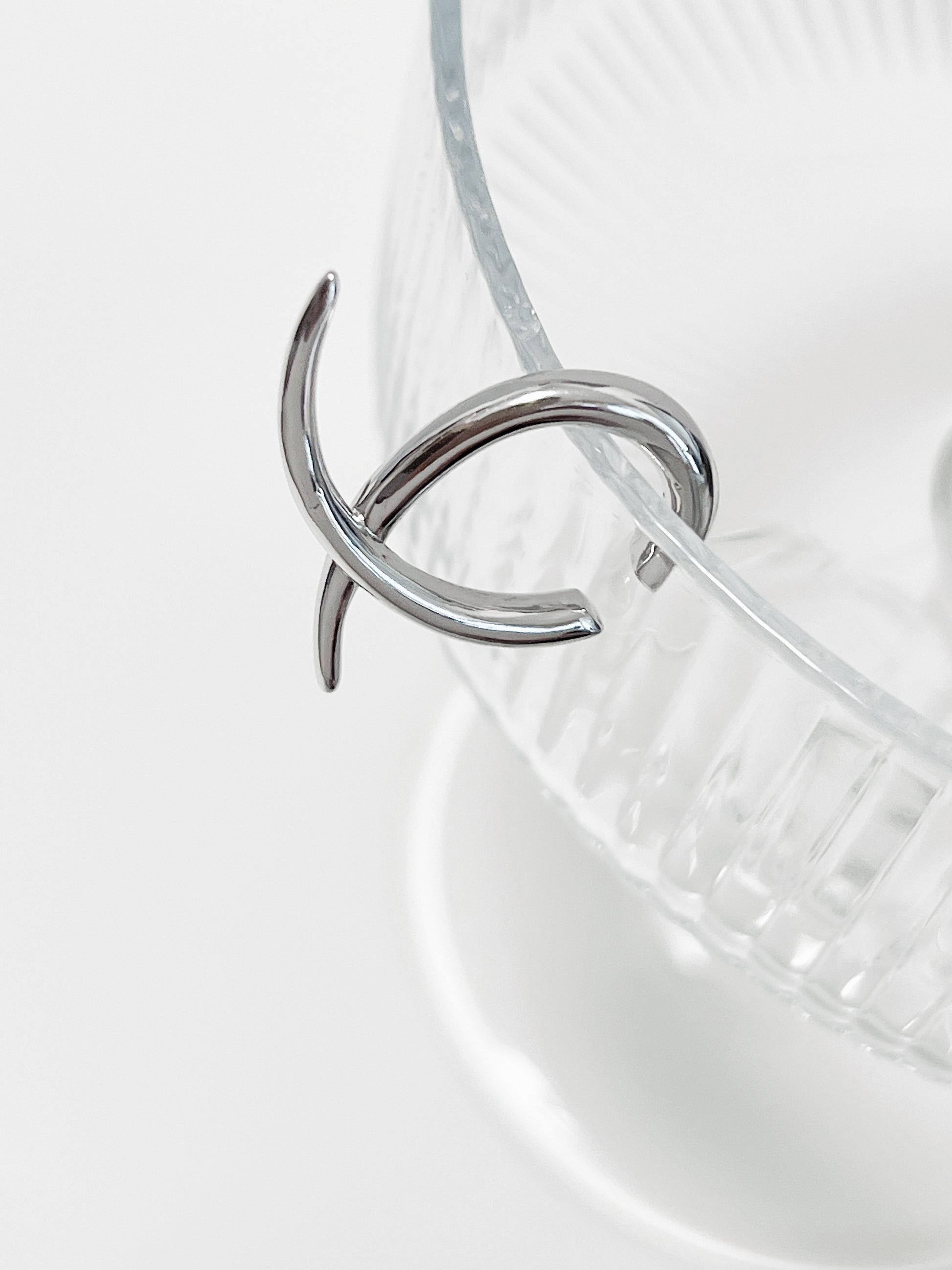 Silver Harley Geometric Cuff on a glass surface highlighting the "X" shape and the luster.