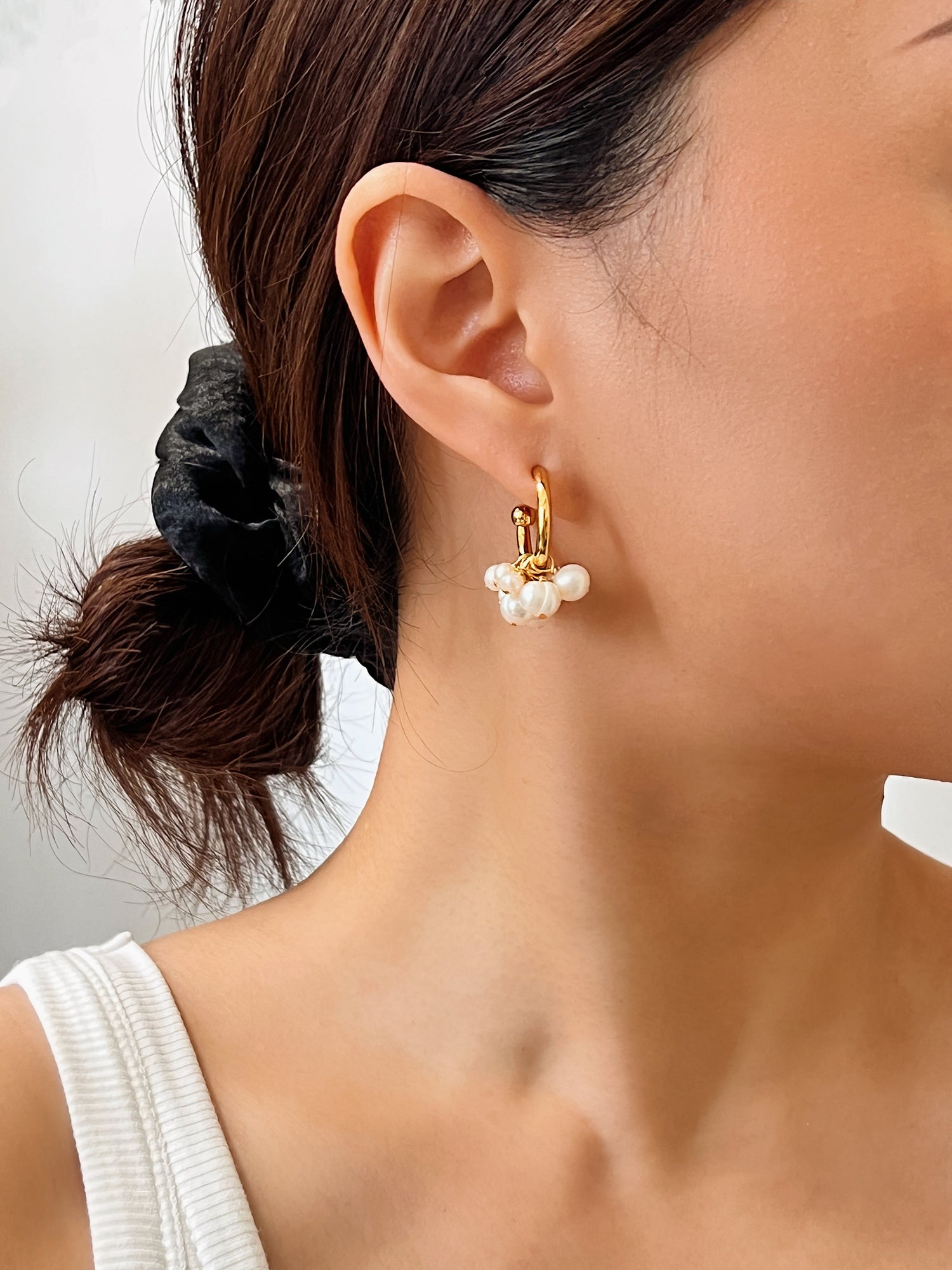 Editorial lifestyle capture of the Freya pearl earrings on model, highlighting a clean beauty look and a sleek low updo hairstyle.