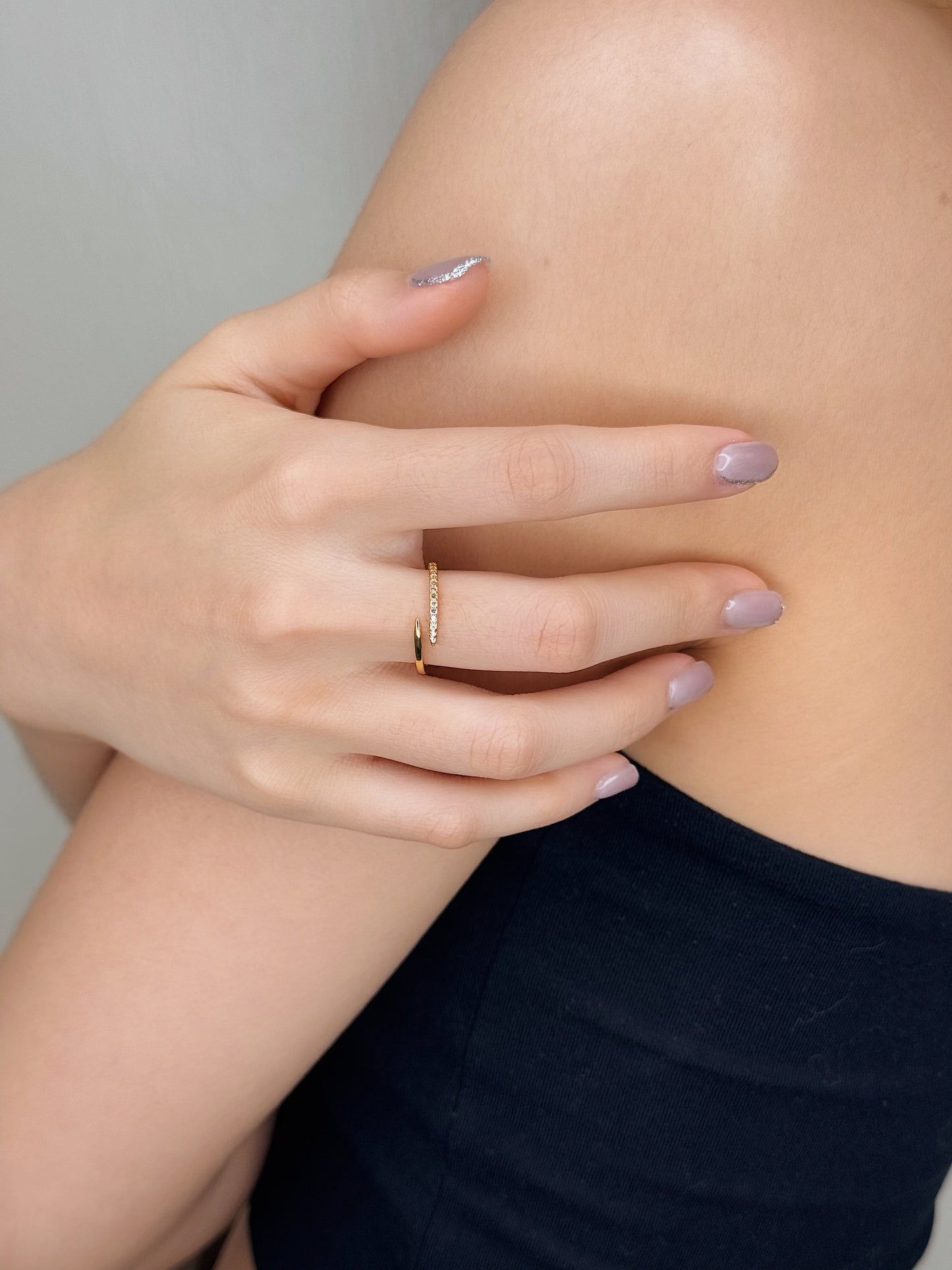 Close up of a model styling an 18k gold pvd bypass ring with clean tailoring