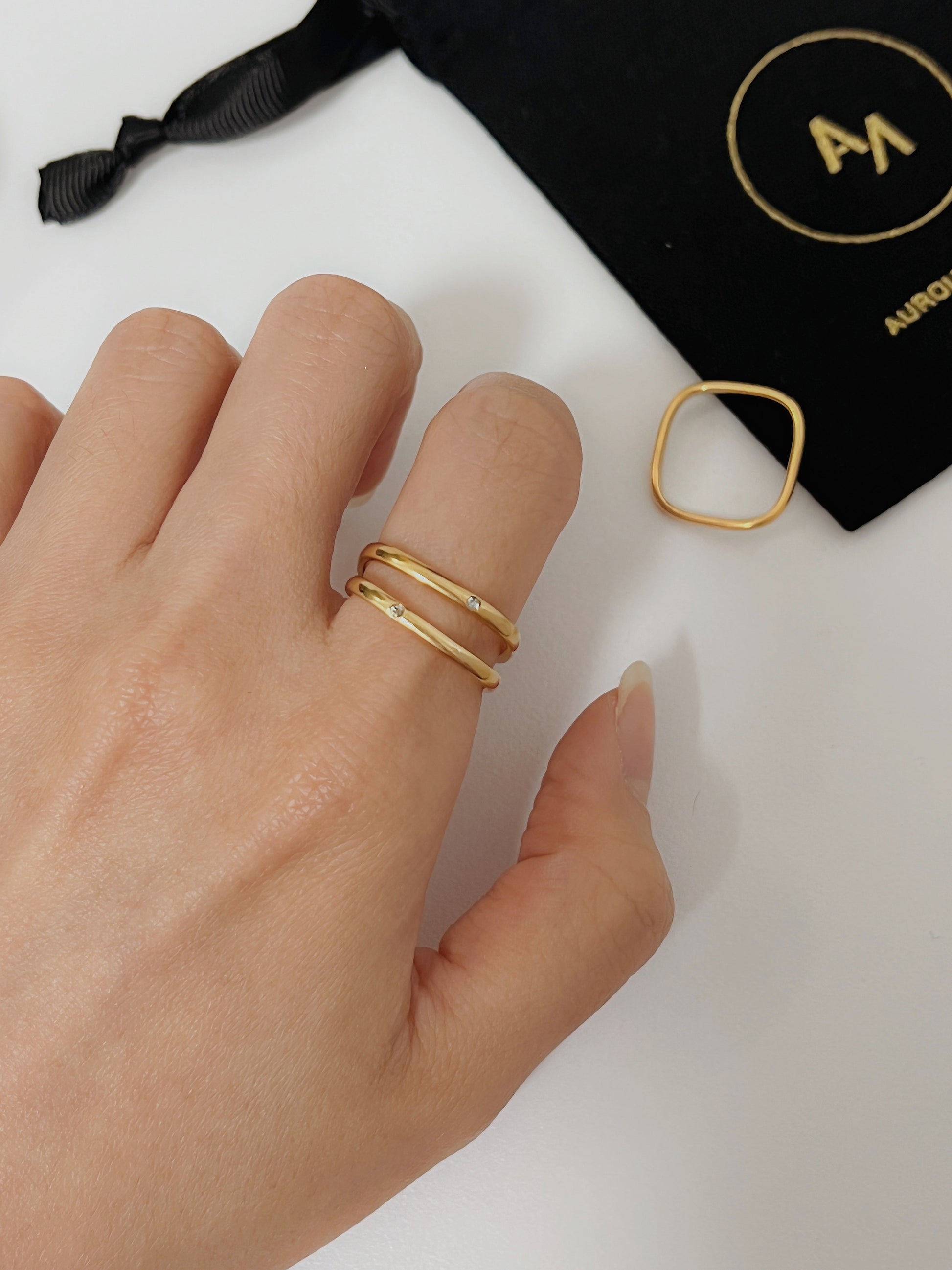 Close up of a model hand styling a gold geometric ring with minimalist tailoring