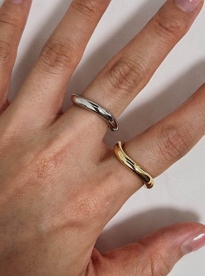 Close up of a model hand styling a rhodium and gold wave ring with minimalist tailoring