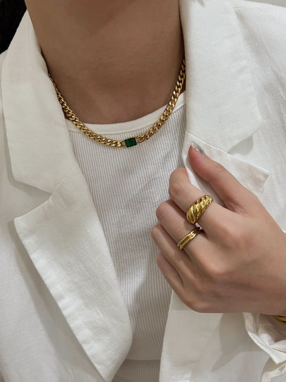 Close up of a woman wearing a rich colored gemstone statement necklace with blazer