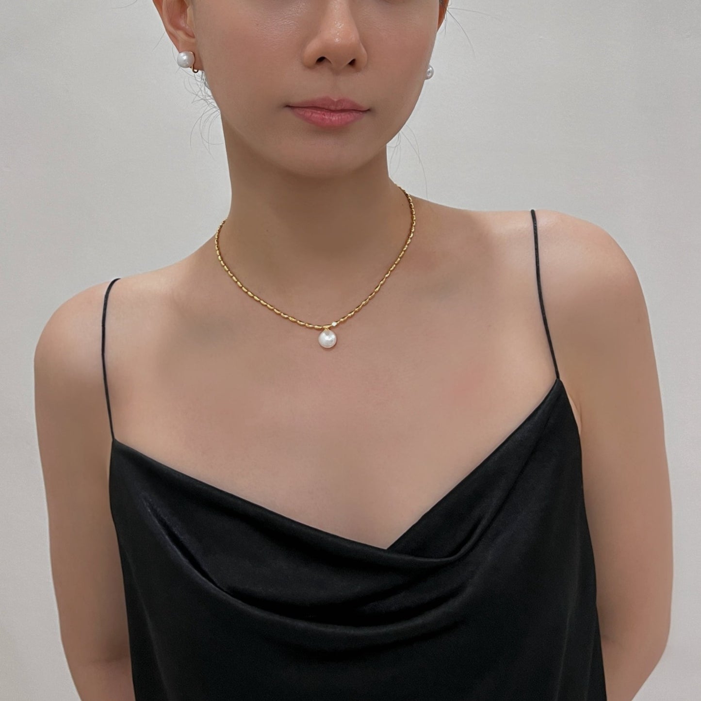 Woman neckline showcasing an elegant sculptural pearl drop choker against smooth sun warmed skin