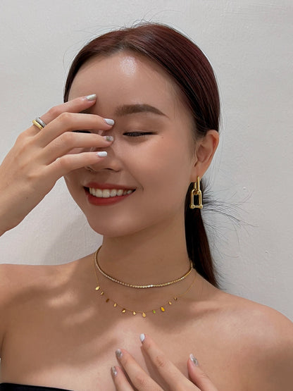 Editorial style jewelry lookbook photo highlighting a reflective gold drop on simple cream summer tank