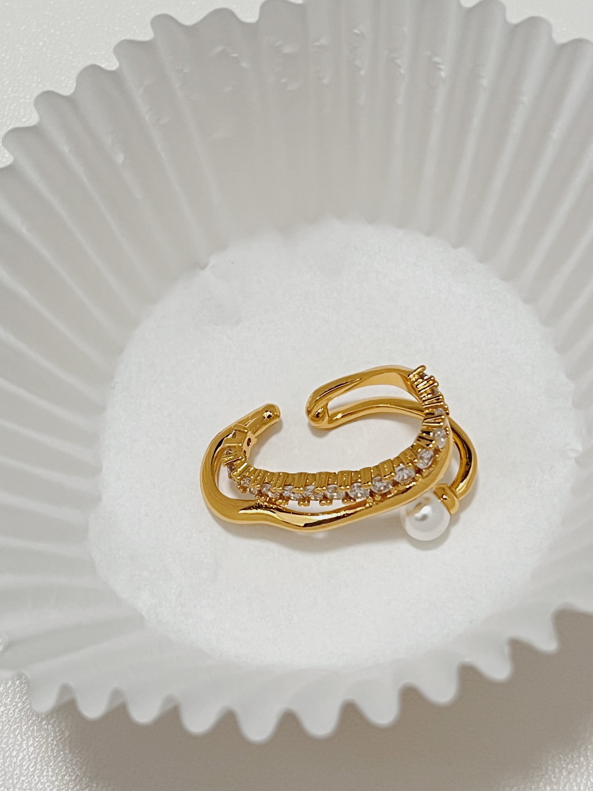 Close-up texture shot of the elegant Cassidy Gold PVD Lobe Cuff Earring, showing the contrast between polished metal, sparkling pave gems, and a lustrous freshwater pearl.