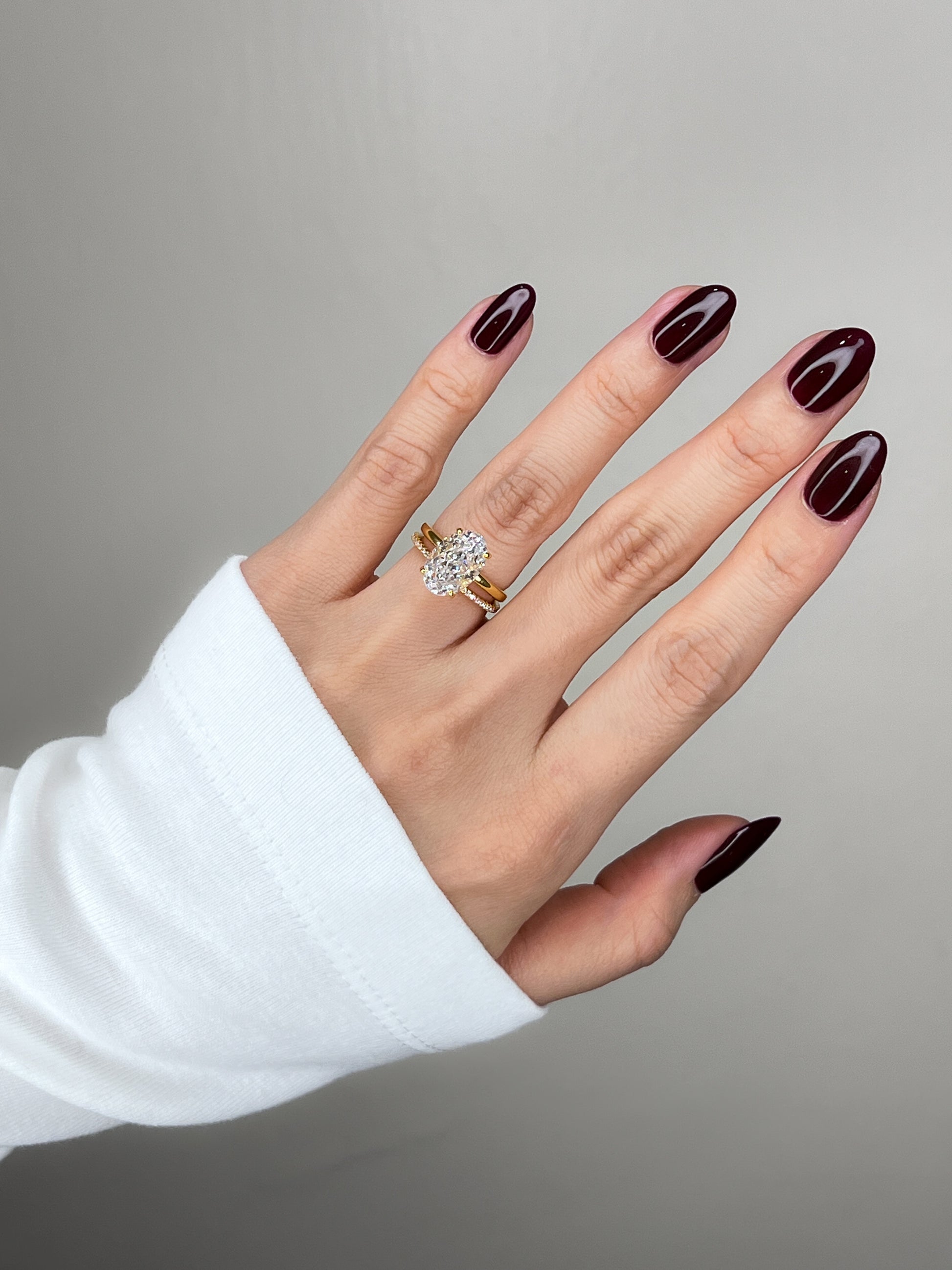 Model wearing Elizabeth 3CT oval gold ring styled with a classic white long sleeve
