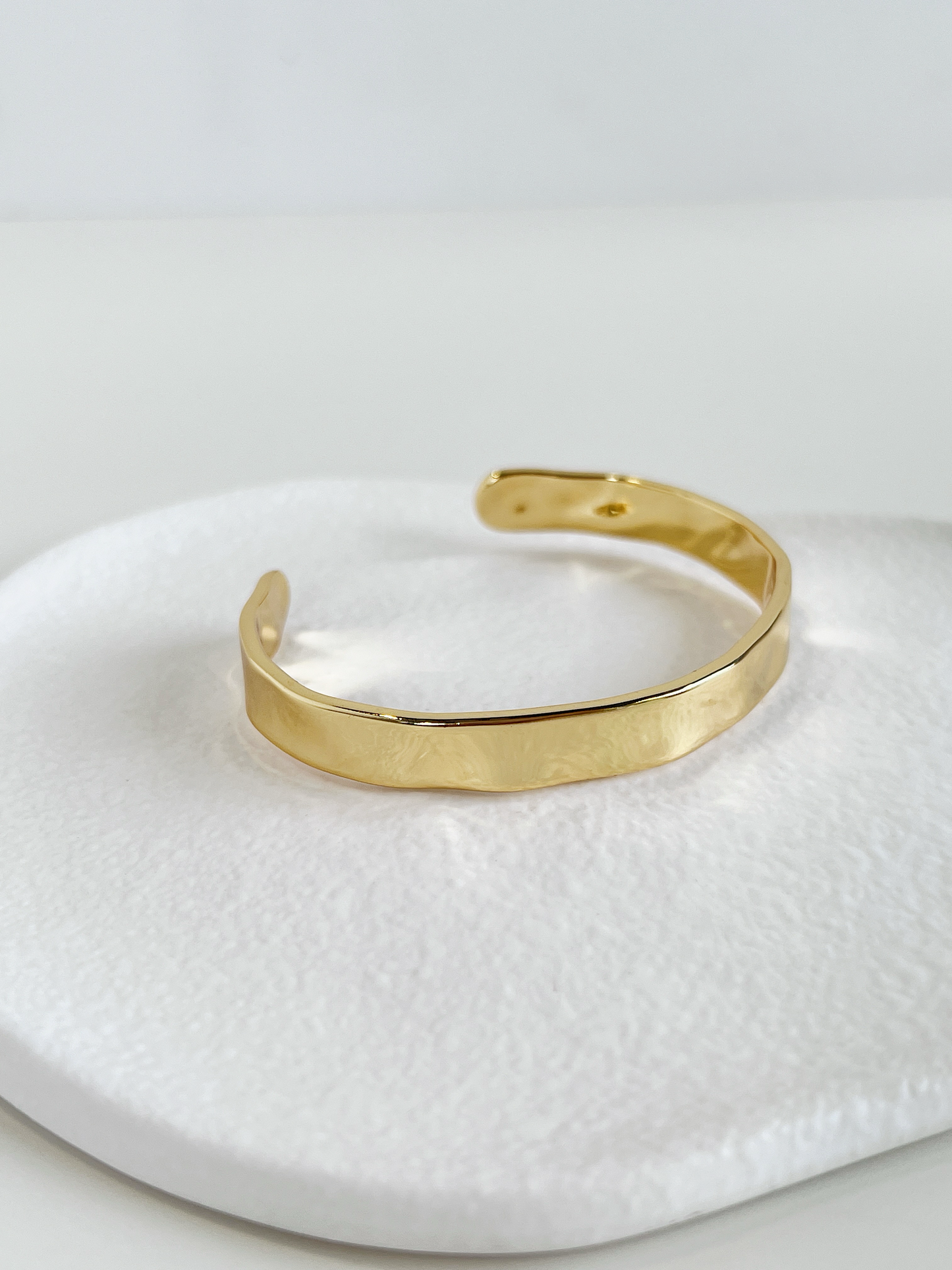 Macro product shot focusing on the distinct uneven surface texture of the Ella 18K gold PVD cuff bangle.
