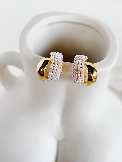 Evadne sculptural pearl crossover earrings showing dual ribbon bands on white surface