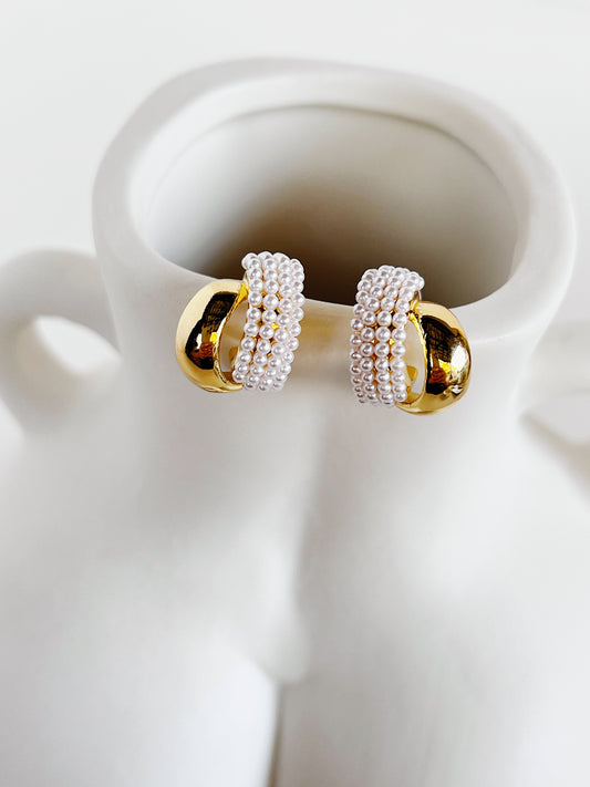 Evadne sculptural pearl crossover earrings showing dual ribbon bands on white surface
