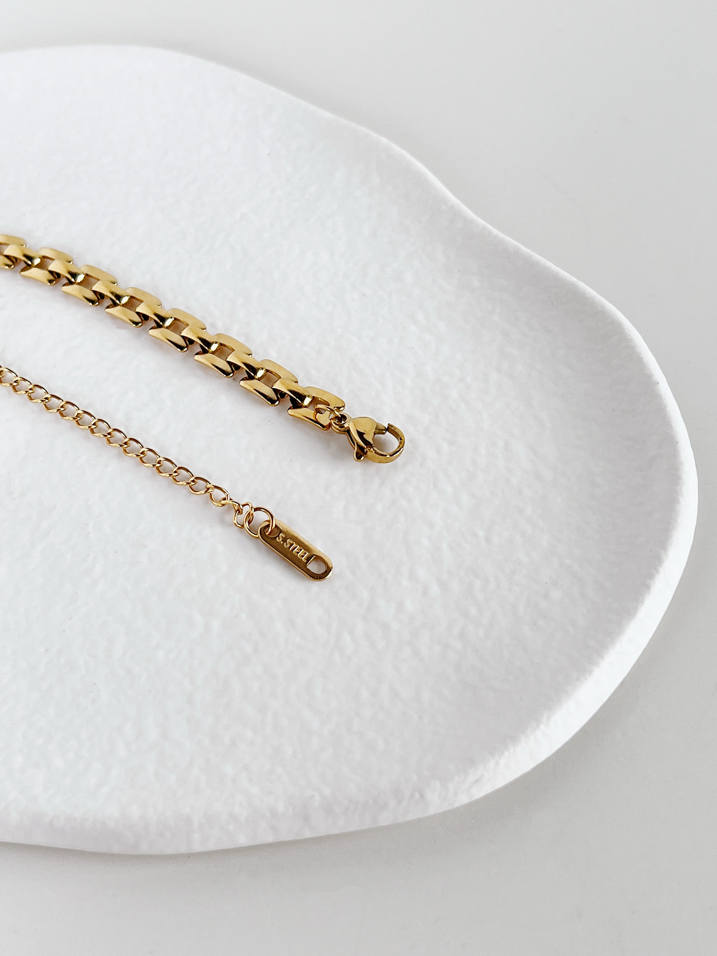 Minimalist studio shot focusing on the slender lobster claw closure and adjustable tail chain of the Evie stainless steel bracelet.